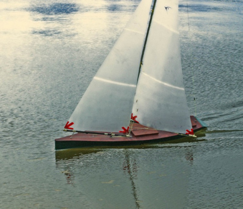 RS1000 model yacht, dark green hull with white translucent sails, smoothly sailing fast through the calm green water. Looks almost like a vintage photograph from times gone by, Location: Sydney, Australia