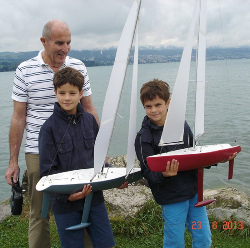 Bill Cobb standing with his two grandkids who are holding model yachts each, Location: Zurich