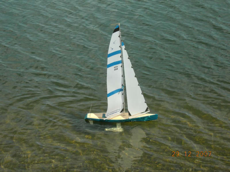 A cyan blue model yacht sailing on a lake, Location: Kaiapoi, New Zealand
