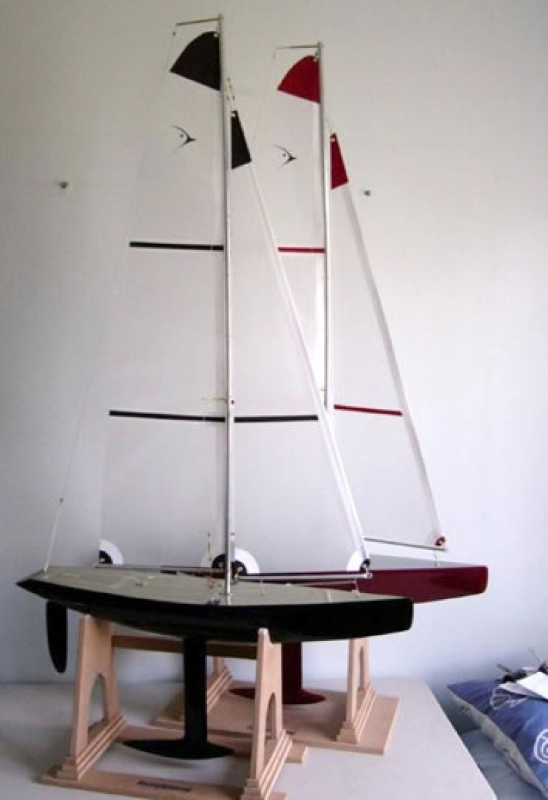 Two racing sparrow model yachts, one red, one black sitting on cradles inside a white room, Location: Australia