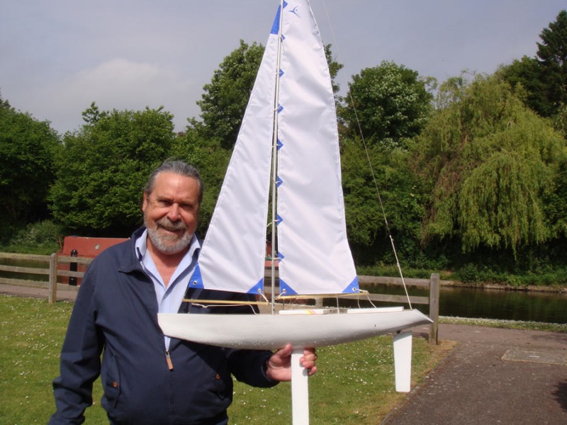 Mel Kitson holding up his white racing sparrow 750 model yacht, Location: Watford UK