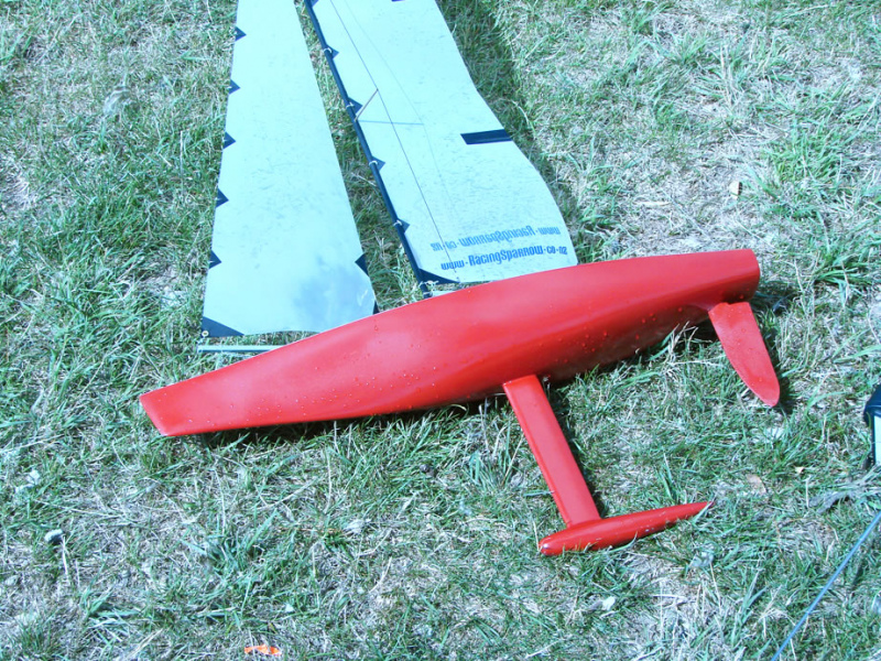 Red Racing Sparrow 750 model yacht lying on the grass with a wet hull, Location: Wellington, New Zealand
